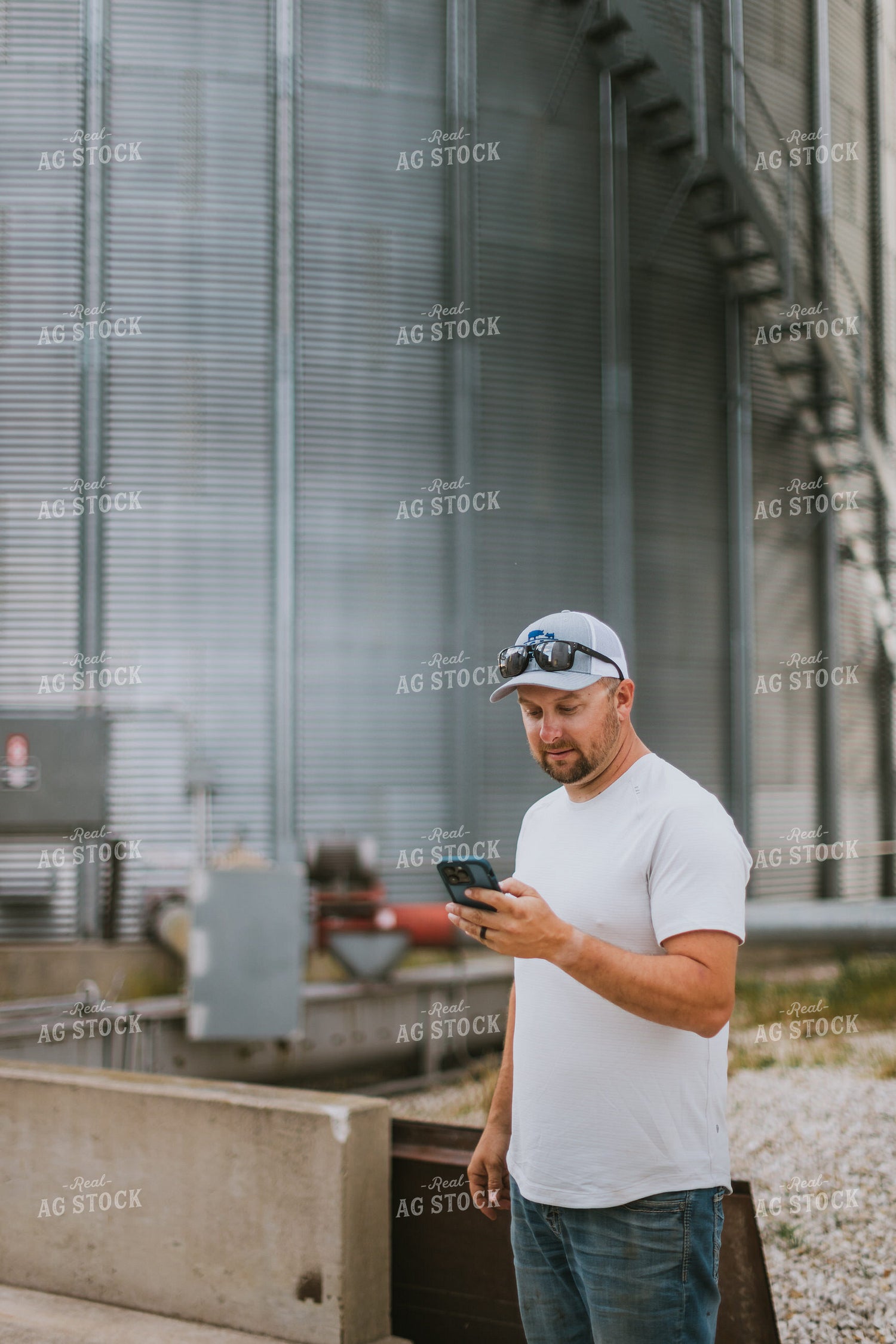Farmer Looking at Phone by Grain Bin 8766
