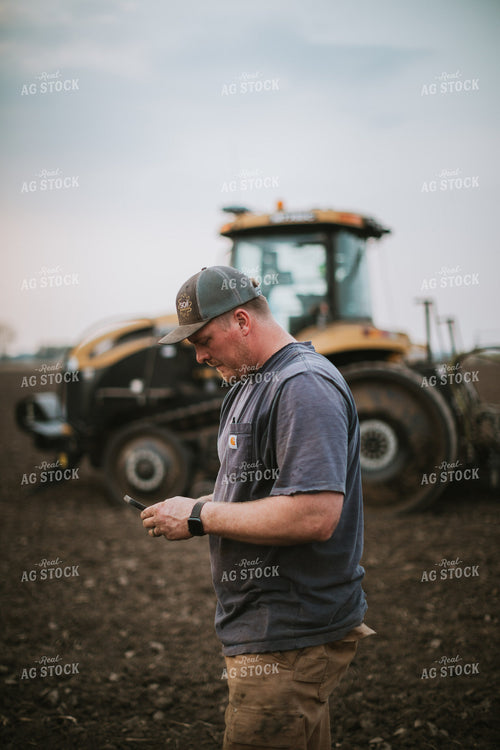 Farmer Looking at Phone in Field with Planter 5673