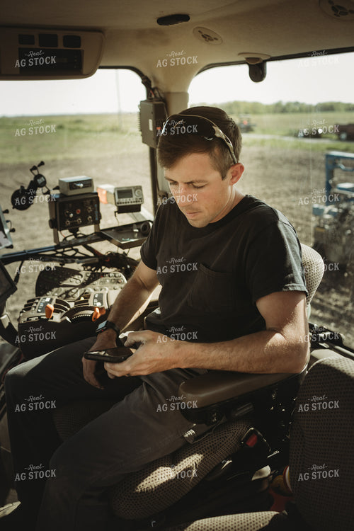 Farmer Looking at Phone in Tractor Cab 4121
