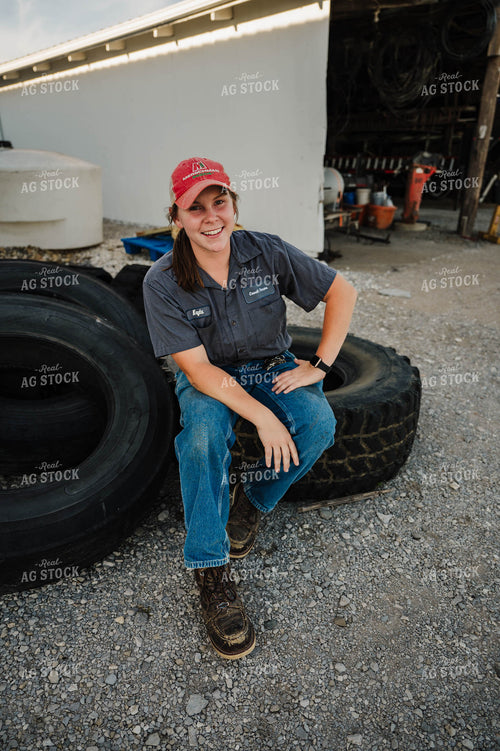 Female Farmer Sitting on Tires 115241
