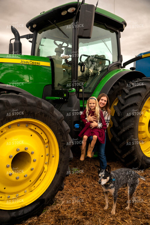 Female Farmer and Daughter Climbing into Tractor 115417